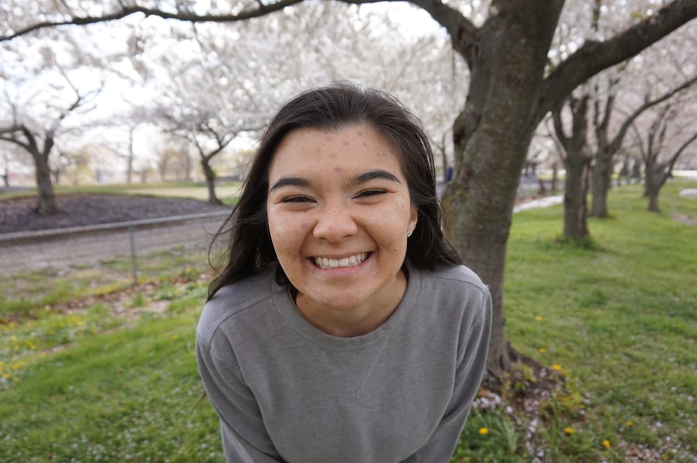 Emily smiling in front of cherry blossom trees