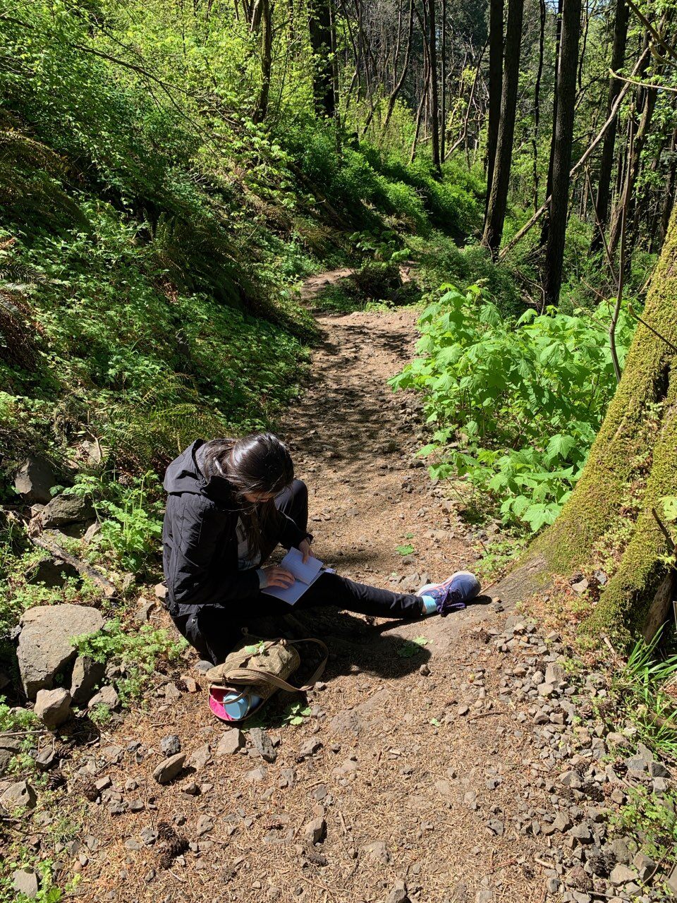 Emily holding a notebook while sitting on a nature trail in Columbia River Gorge