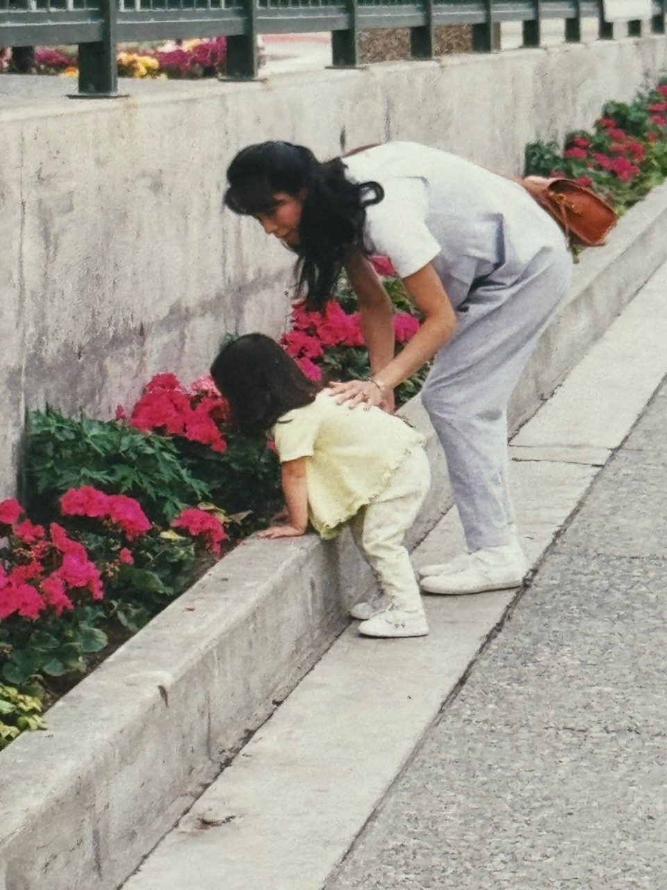 Angela and one-year-old Emily Bell in Anchorage, Alaska, smelling red and pink flowers